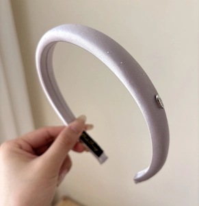 Detail view of light purple satin padded headband with silver Love metal plate