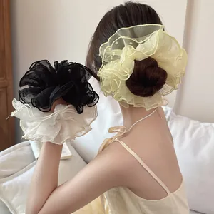 Dettaglio di elastici scrunchie oversize in pizzo a pois gialli, neri e bianchi