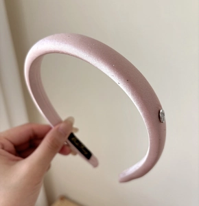 Close-up of pink satin padded headband with silver Love metal charm and smooth texture