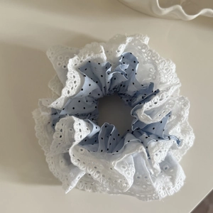 Détail d'un chouchou en tissu bleu à pois avec broderie en dentelle blanche raffinée