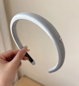 Detailed macro view of silver-grey satin headband featuring a Love engraved metal charm