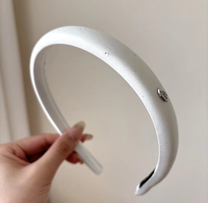 Detail of white satin padded headband featuring a silver metal plate with LOVE engraving