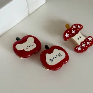 Cute red apple hair clips with cartoon cat and bear patterns on a gold metal base