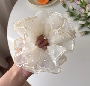 Dettaglio dell'elastico per capelli oversize in organza crema con pois bianchi e volant