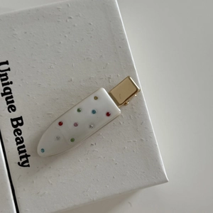 Detail view of popsicle shaped acetate hair clip with multicolored rhinestones and gold base