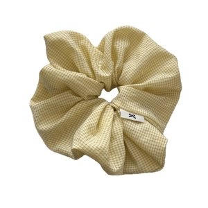 Oversized yellow gingham scrunchie with a minimalist woven label on a white background