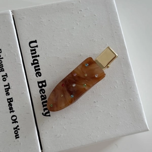 Macro detail of tortoiseshell acetate hair clip with colorful rhinestones and gold metal base