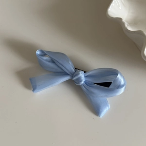 Détail d'un nœud papillon en satin bleu clair avec texture lisse sur fond minimaliste