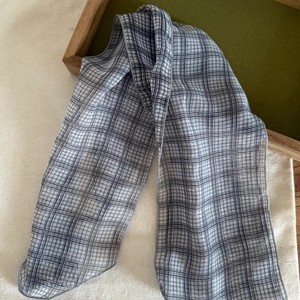 Détail d'un foulard en lin à carreaux sur plateau en bois avec tissu et coutures fines