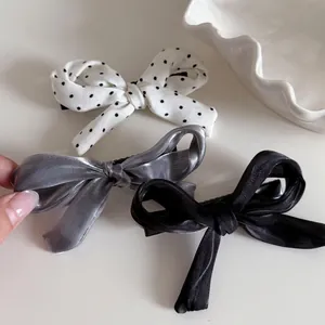 Lot de trois barrettes à nœuds doux en satin et à pois sur un plateau blanc élégant