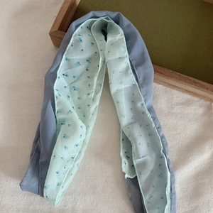 Détail de l'écharpe en soie et lin montrant le motif floral bleu et le tissu léger