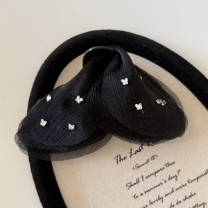 Détail d'une pince à cheveux en tulle plissé noir avec papillons en strass brillants