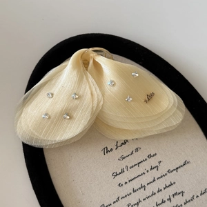 Détail de la pince à cheveux papillon en tulle champagne avec strass brillants et breloque Love