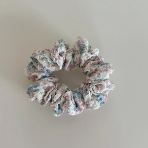 Dettaglio dello scrunchie a fiori rosa con tessuto a balze e fascia elastica interna
