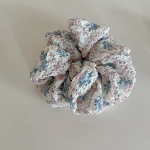 Dettaglio ravvicinato della trama e del motivo floreale rosa e blu dell'elastico per capelli