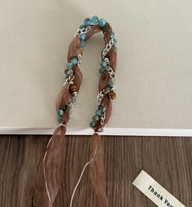 Détail d'un bandeau bohème tressé avec perles turquoise et rubans en organza brun