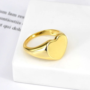 Polished gold plated heart signet ring for men and women on a minimalist pedestal