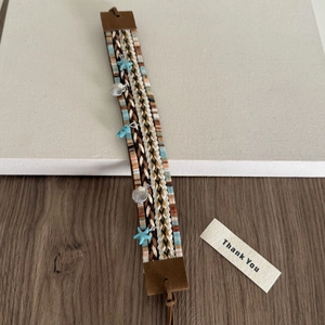 Détail du bandeau tressé bohème avec breloques étoile de mer et coquillage argenté