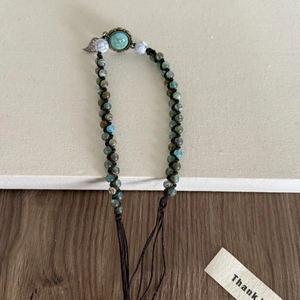Détail d'un bracelet tissé bohème fait main avec perles turquoise et breloques en bronze