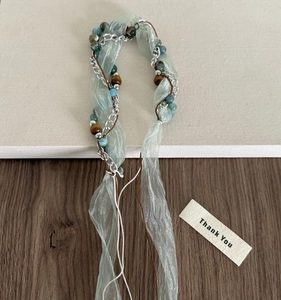 Détail d'un bandeau bohème avec ruban d'organza, chaîne argentée et perles minérales bleues