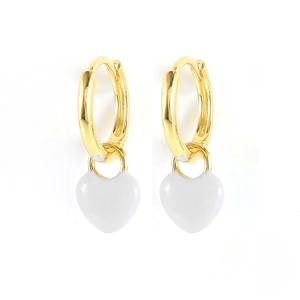 Detail view of gold hoop earrings featuring white enamel heart-shaped charms