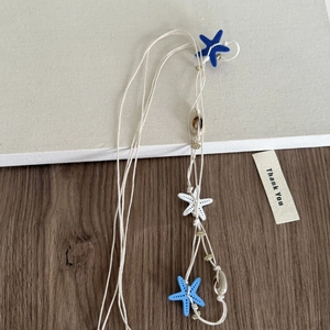Détail du collier de plage avec des étoiles de mer bleues et des coquillages