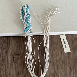 Détail de perles turquoise bohèmes et corde tissée blanche à longs glands