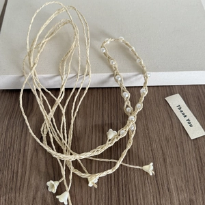 Détail d'un bandeau bohème fait main avec perles et breloques de muguet en résine