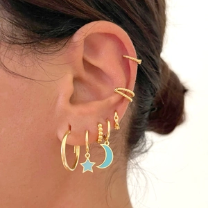 Close-up van gouden ster oorbellen met blauw emaille op het oor voor een stijlvolle look