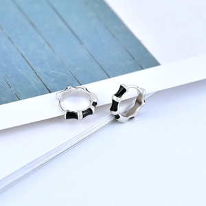 Detail of S925 silver bamboo hoop earrings with black enamel drip in a modern geometric style