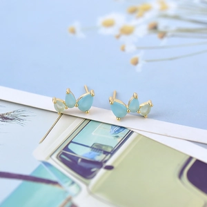 Close-up of wing-shaped stud earrings with light blue and green gradient zircons