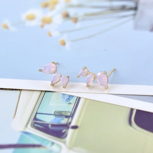 Detailed macro of gold butterfly wing earrings with pink teardrop gradient zircon stones