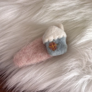 Dettaglio molletta in feltro rosa con motivo a casetta su sfondo in peluche morbido