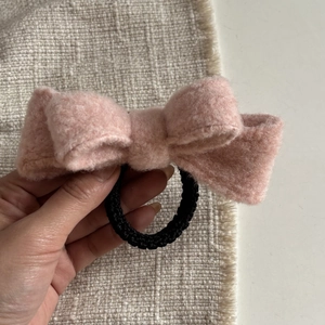 Detail of pink fleece bow hair scrunchie with a black elastic band for high ponytails