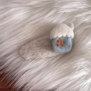 Fermaglio per capelli in lana cotta a forma di casa con neve su sfondo di peluche bianco