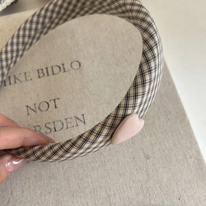 Detail of vintage beige and blue plaid headband featuring a matte pink heart decoration