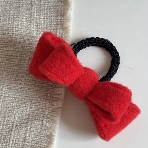 Detail shot of the red wool bow hair tie with high-quality texture and black elastic band
