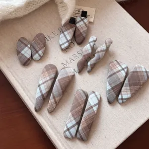 Detailed close-up of brown plaid fabric hair clips in various shapes on a cozy background