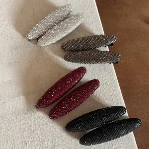 Détail de barrettes à cheveux étincelantes en strass argent, gris, bordeaux et noir