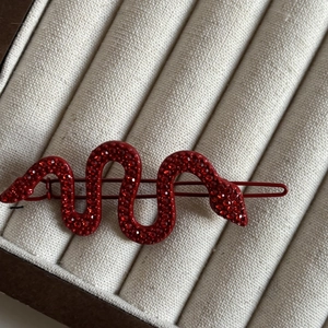 Close-up of red snake hair clip with pavé rhinestones on a soft velvet jewelry box