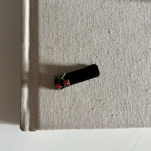 Detailed view of a black velvet hair clip with 3D red cherry accents and green leaves