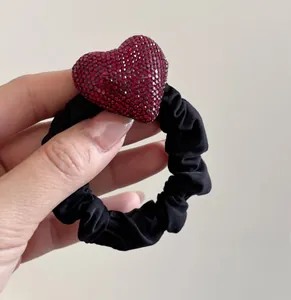 Dettaglio dell'elastico per capelli nero con grande cuore di strass rossi