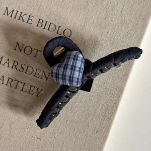 Detail of blue plaid heart fabric hair claw clip with golden metal spring on canvas background