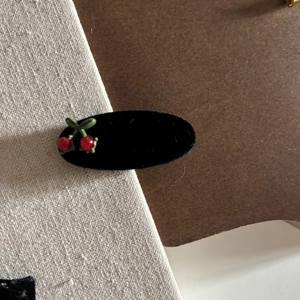 Detail of vintage black velvet hair clip with red cherry ornament and green leaves