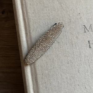 Vue détaillée de la barrette à cheveux en strass étincelants sur un livre en tissu minimaliste