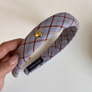 Detailed close-up of blue plaid headband featuring a gold heart charm and handmade label