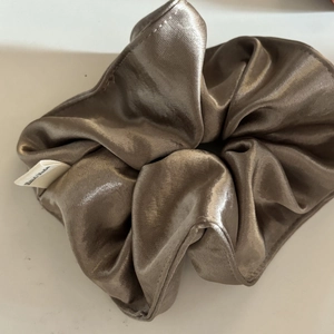 Detail of a champagne satin scrunchie with a white Hand Made tag and smooth texture