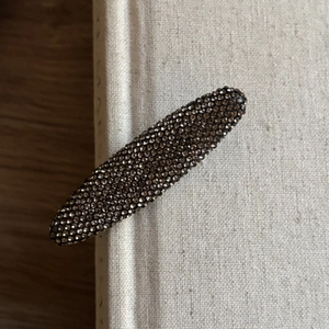 Gros plan d'une pince à cheveux en strass rouge foncé sur un livre vintage