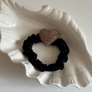Macro di un elastico nero con un grande cuore di strass color champagne su un vassoio a conchiglia