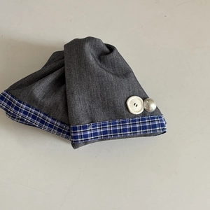 Detailed view of grey fabric hair clip with blue plaid trim, pearl and white button